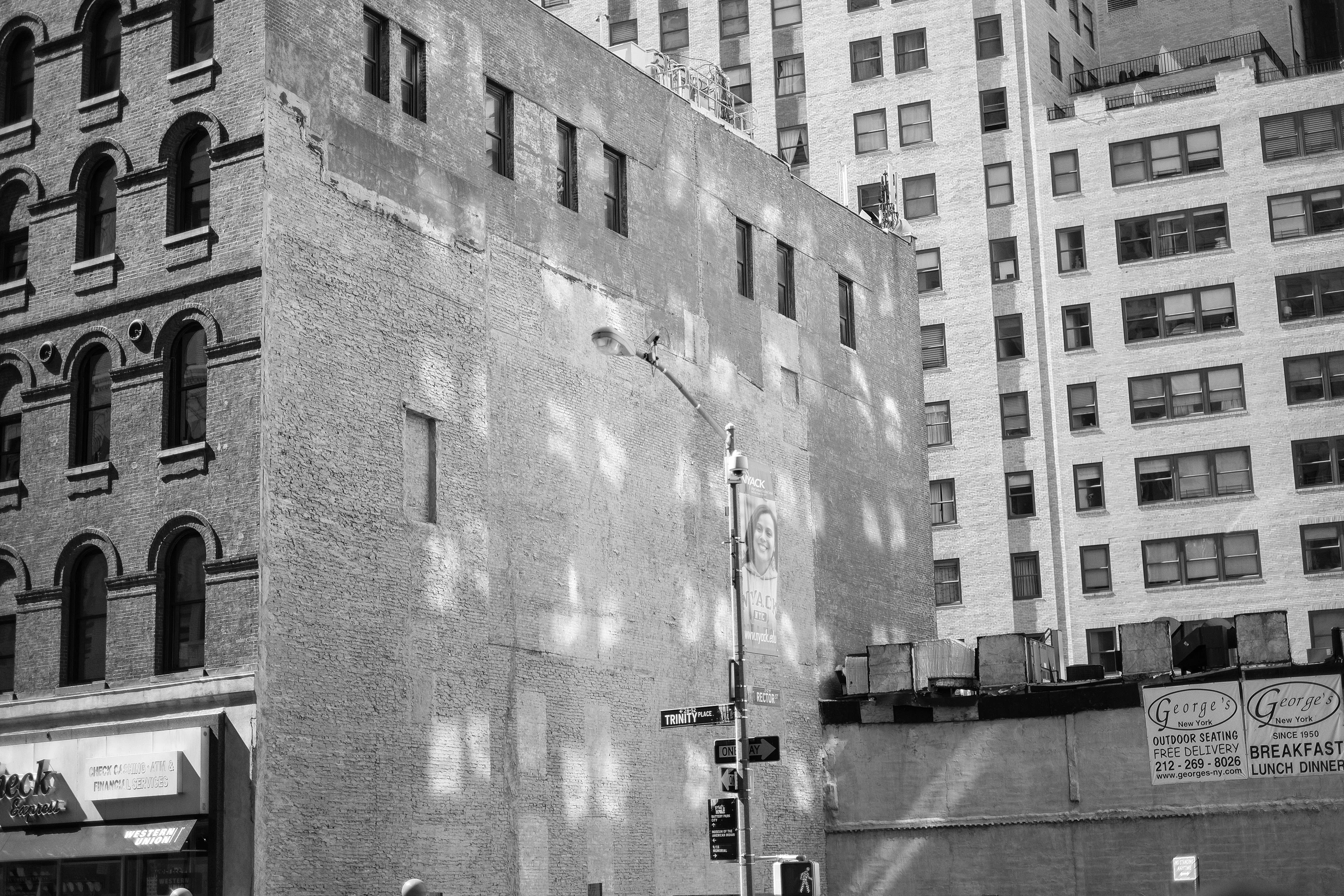 Urban scene with old and modern buildings, featuring a street lamp and signs at an intersection.