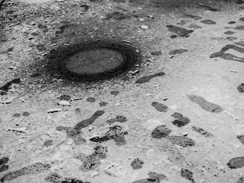 Footprints in the snow surrounding a manhole cover.