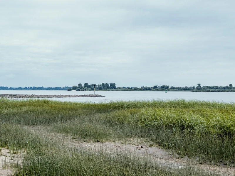 A scenic coastal landscape with a red lighthouse by the water's edge.