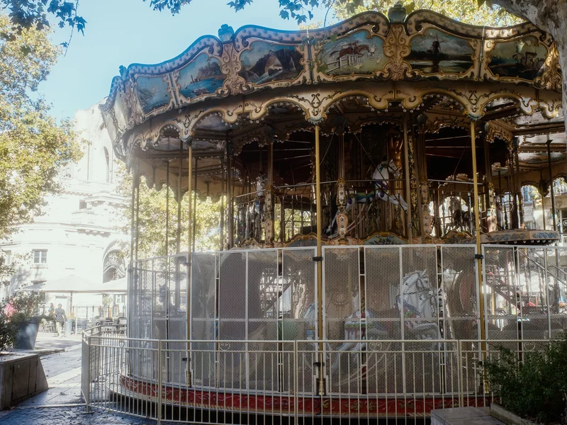 A vintage carousel under the shade of trees in an outdoor setting.