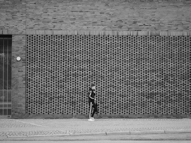 Person walking along a patterned brick wall.