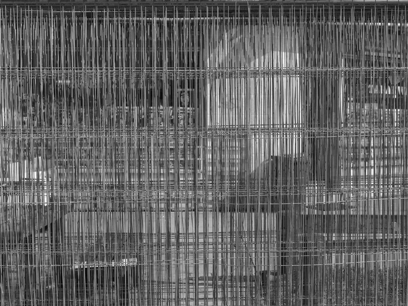 A dense metal wire grid in grayscale with intersecting vertical and horizontal lines.