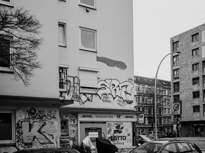 Street view with graffiti-covered building facade and modern apartments.