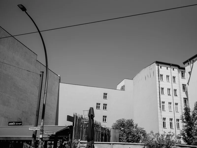 Black and white urban scene with tall buildings, a streetlight, and street signs.
