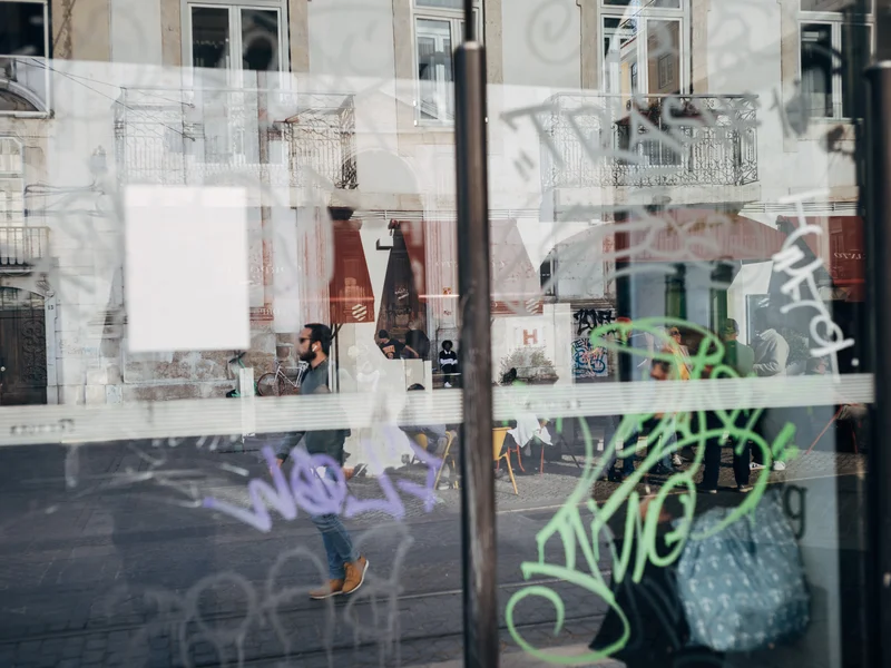 Reflection of urban street scene with graffiti on glass and people walking.