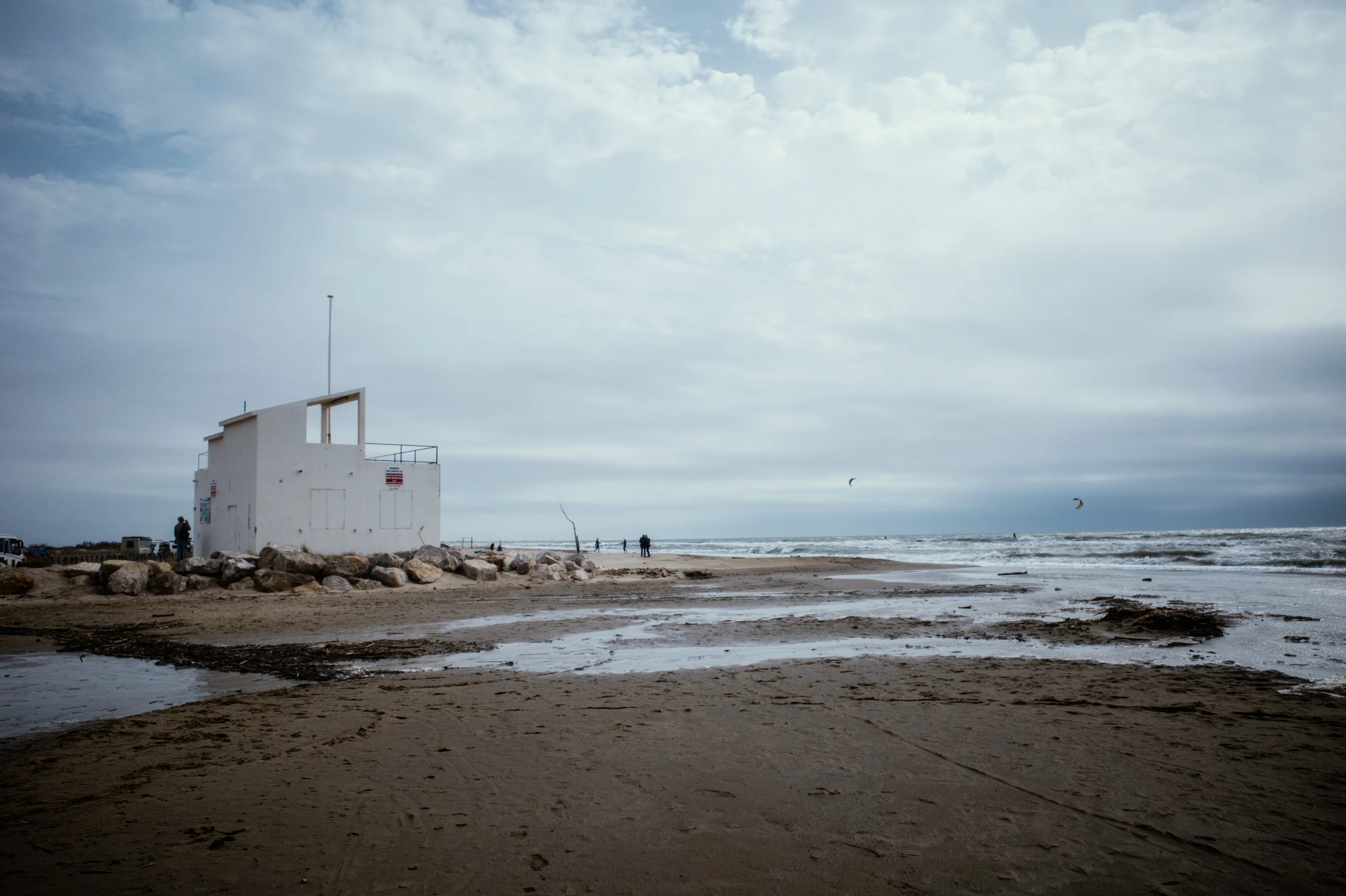 A white building on a rocky beach under a cloudy sky.