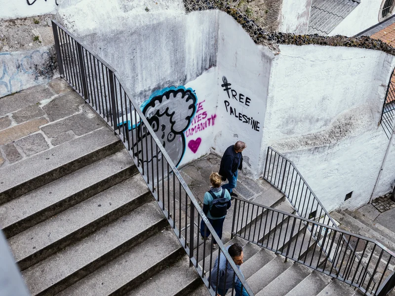 People walking down outdoor stairs with graffiti on the walls in an urban setting.